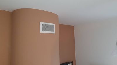Coin intérieur d'une pièce aux murs pêche et blancs et un petit tableau encadré près du plafond