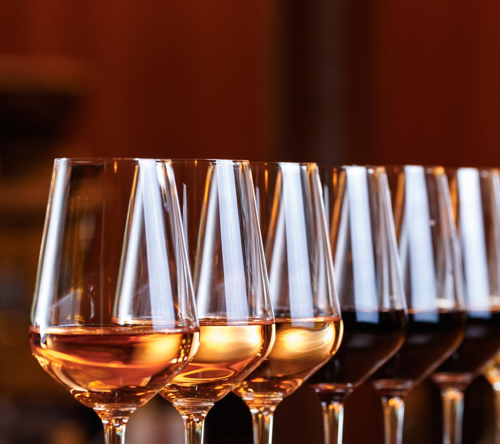 Deux personnes trinquent avec des verres de vin rouge autour d'une table à dîner, avec des bougies et des aliments flous en arrière-plan.