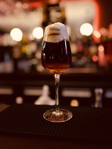 Un groupe de personnes rient et trinquent avec des verres de vin à la table d'un restaurant à l'éclairage tamisé.