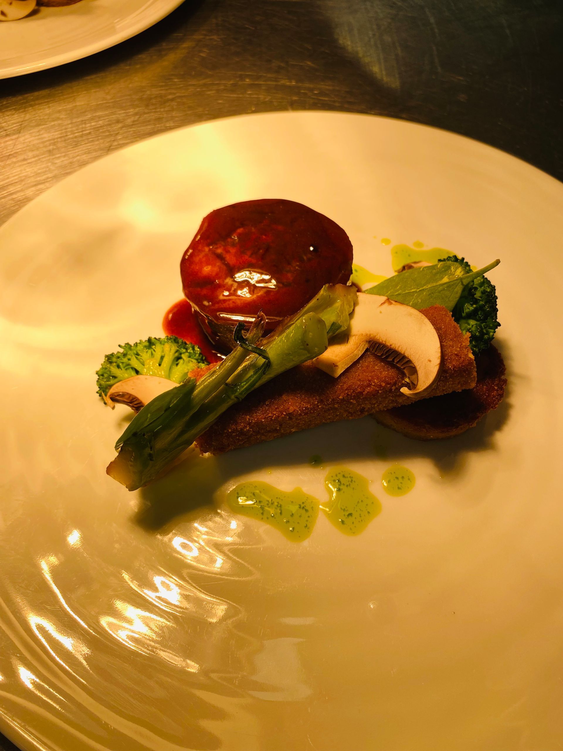 Gros plan sur un chou à la crème fourré à la crème pâtissière, nappé de caramel et de noix, présenté sur une assiette blanche avec d'autres choux en arrière-plan.