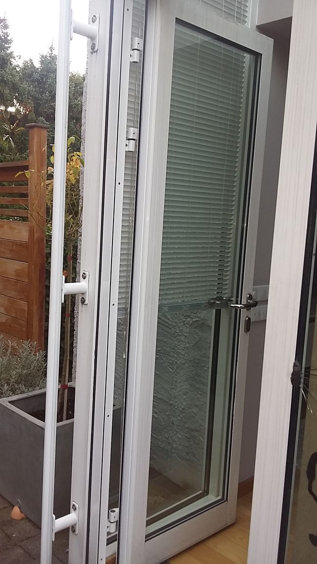 Ein weißes Fenster mit der Spiegelung eines Hauses darin.