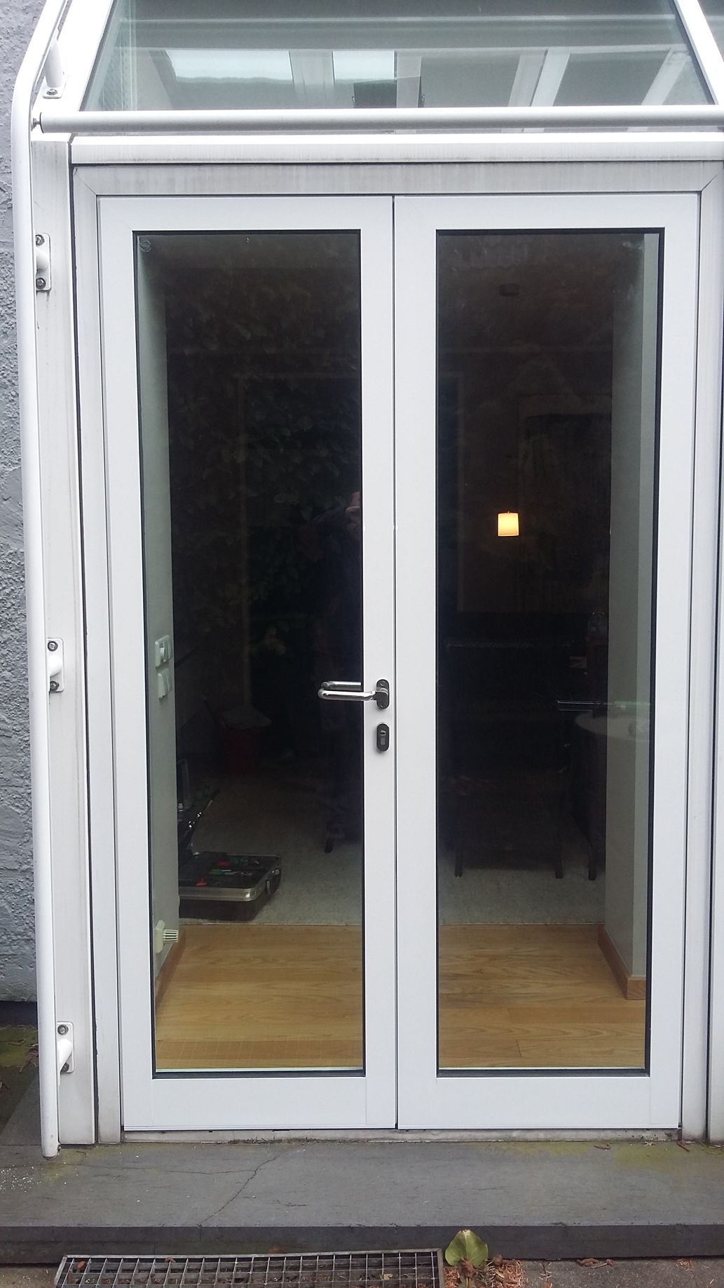 Ein weißes Fenster mit der Spiegelung einer Lampe darin.