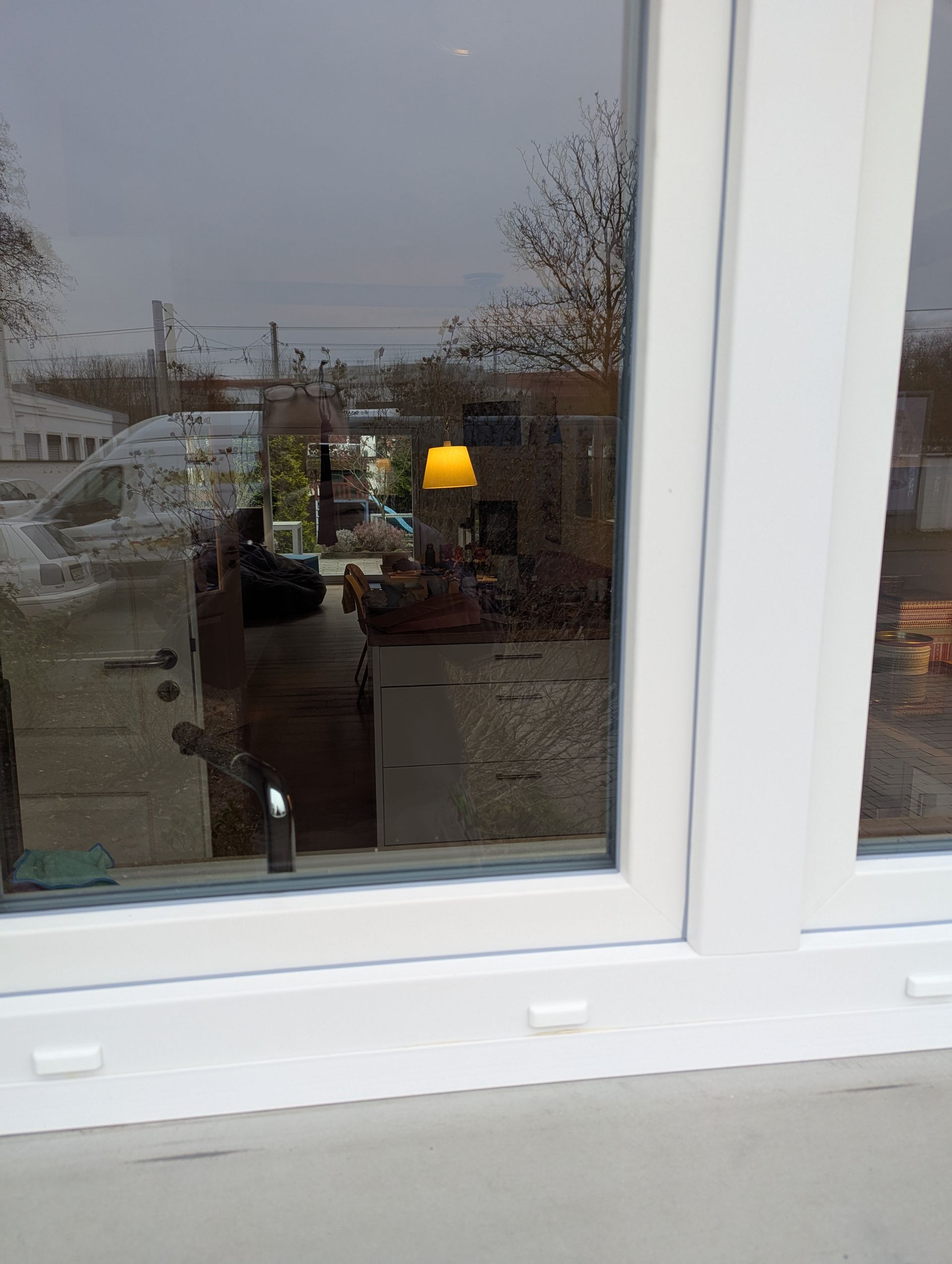 Ein weißes Fenster mit der Spiegelung eines Hauses darin.