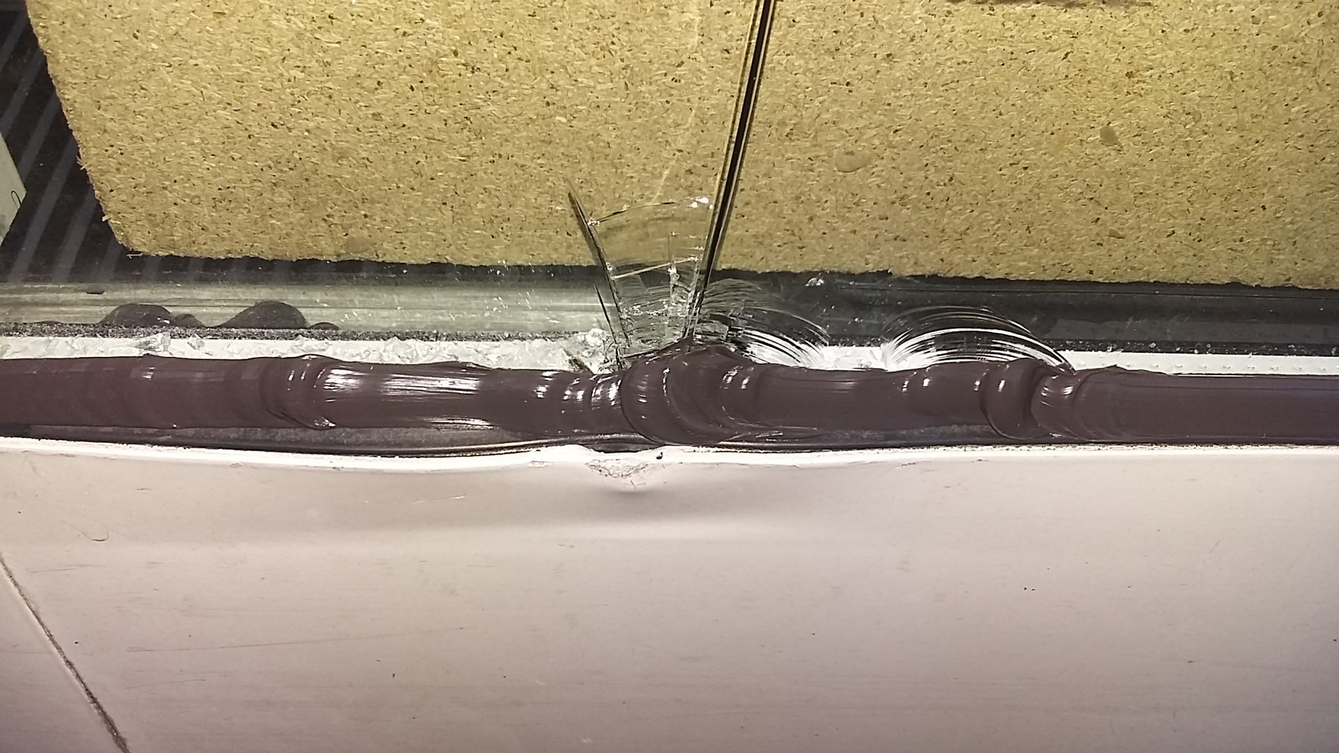 Eine Nahaufnahme eines zerbrochenen Fensters mit einem Loch darin.