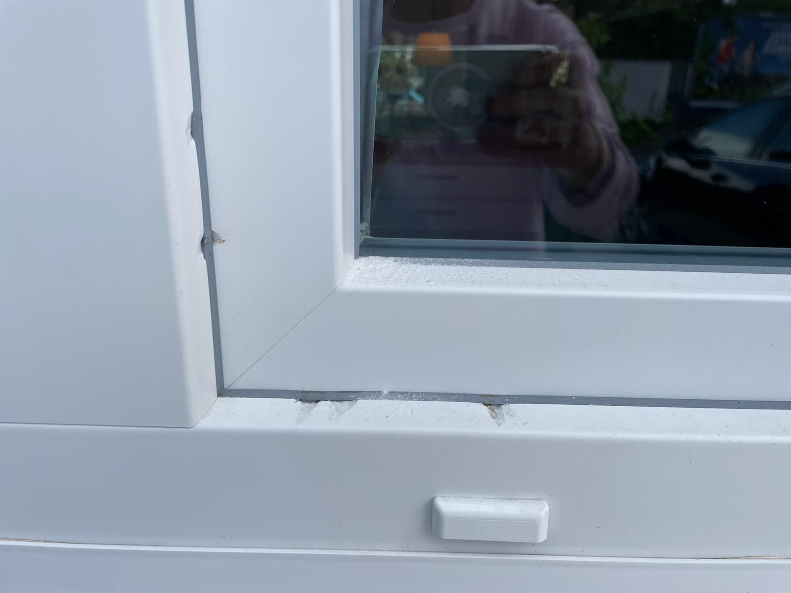 Eine Nahaufnahme eines weißen Fensters mit der Spiegelung einer Person darin.