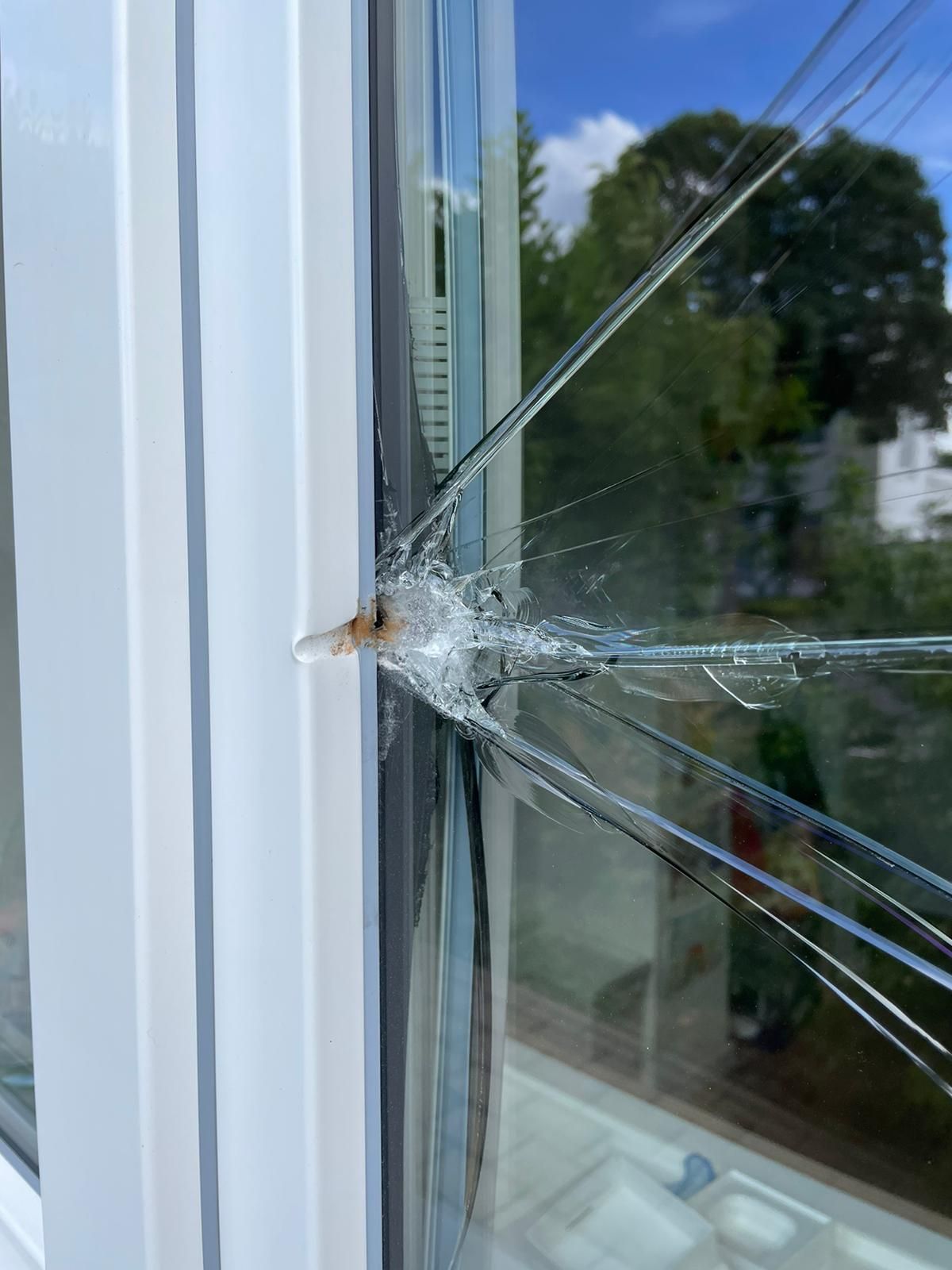 Eine Nahaufnahme eines zerbrochenen Fensters mit einem Loch darin.