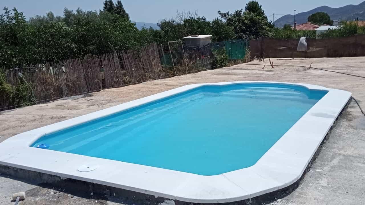 Una gran piscina azul se encuentra encima de un patio de hormigón.