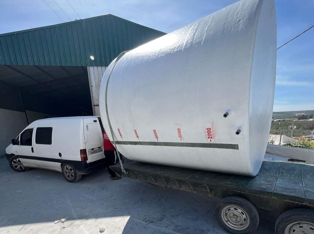 Una camioneta blanca está estacionada al lado de un gran objeto blanco en un remolque.