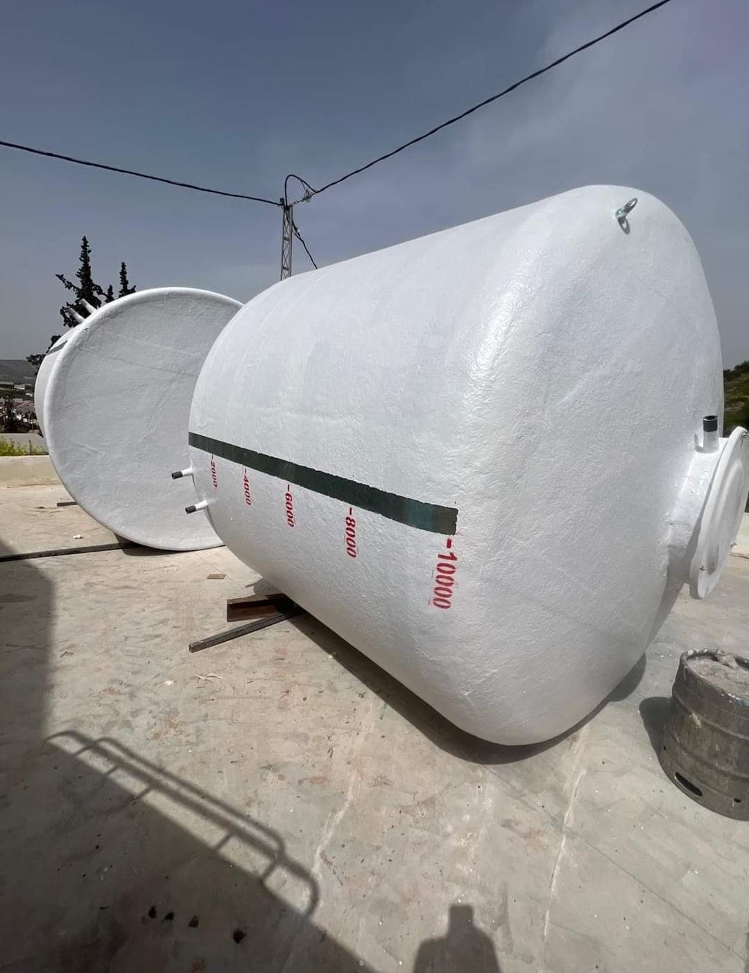 Dos grandes tanques blancos están sentados uno al lado del otro en el suelo.
