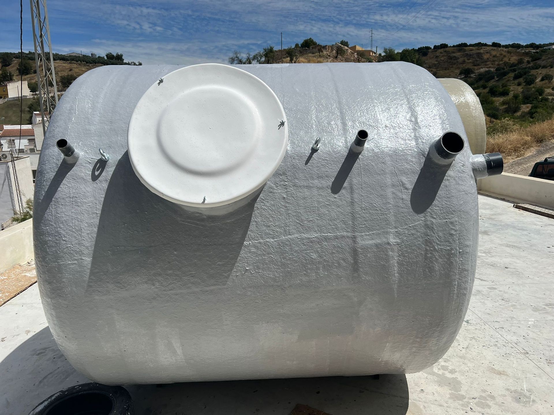 Un gran tanque blanco con una tapa blanca está sentado sobre una superficie de concreto.