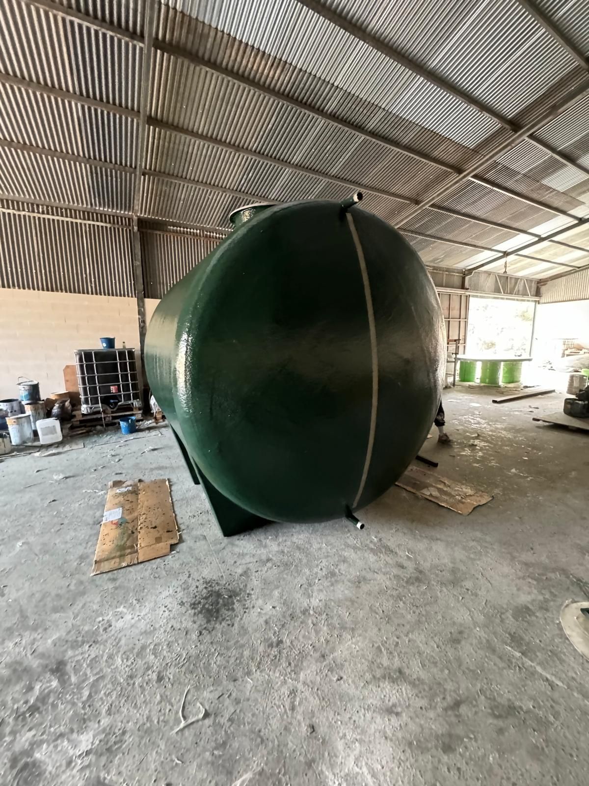 Un gran tanque verde está en un almacén.