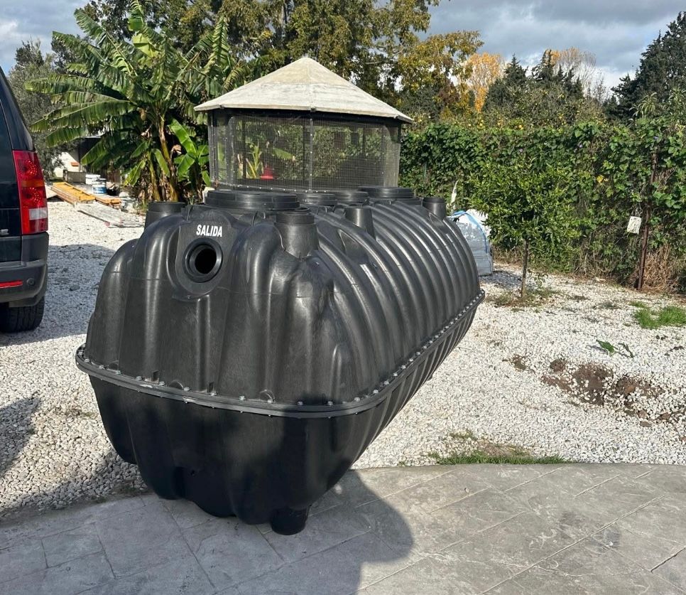 Un gran tanque séptico negro está al costado de la carretera.