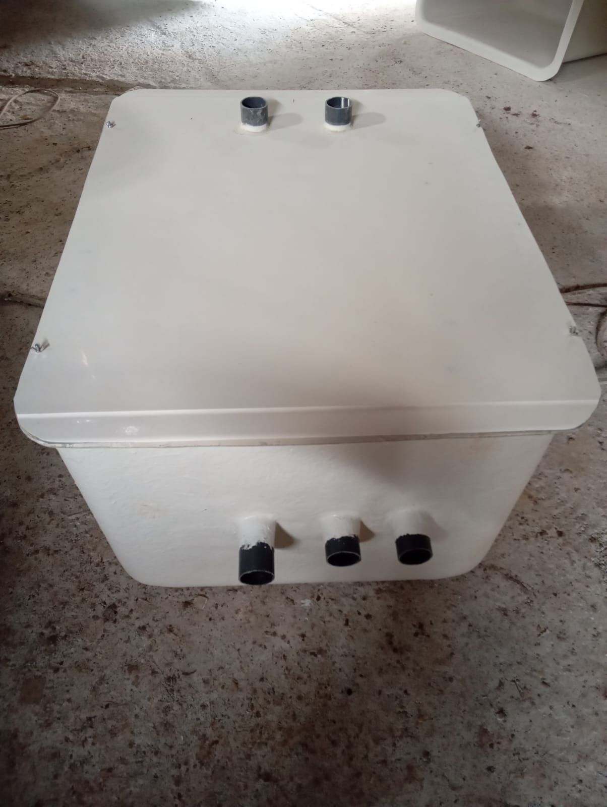 Una caja blanca está sobre un piso de concreto.