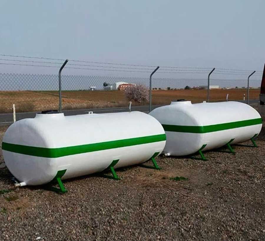 Dos tanques blancos con rayas verdes están sentados en un área de grava.