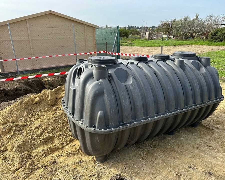 Tanque séptico negro en una excavación cerca de un edificio.