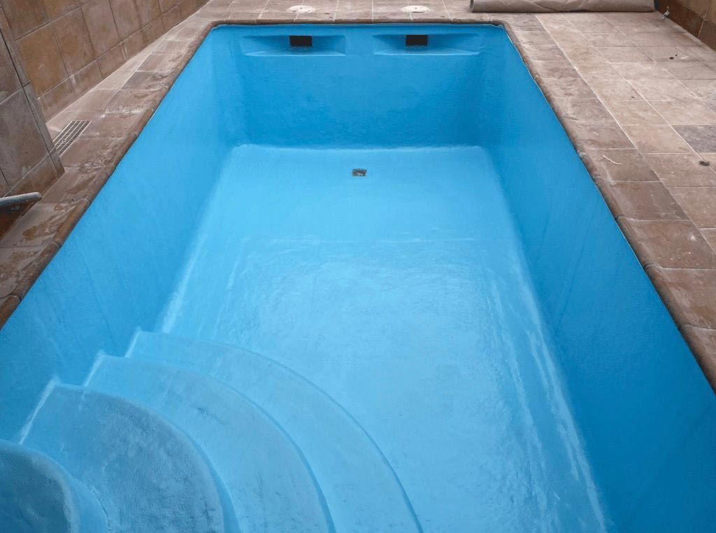 Una piscina frente a una casa con techo azul