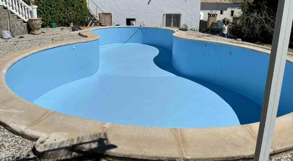 Una piscina frente a una casa con techo azul
