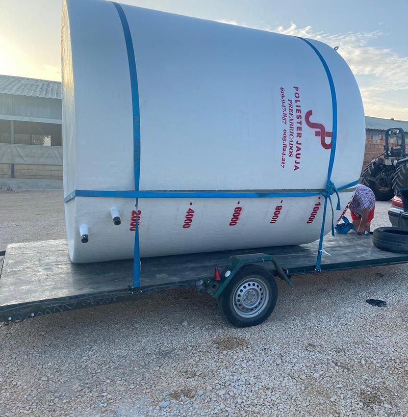 Un gran tanque de agua blanca está atado a un remolque; una persona al volante se encarga de él.