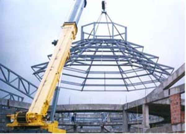 Grúa amarilla elevando una estructura de acero en una obra de construcción.