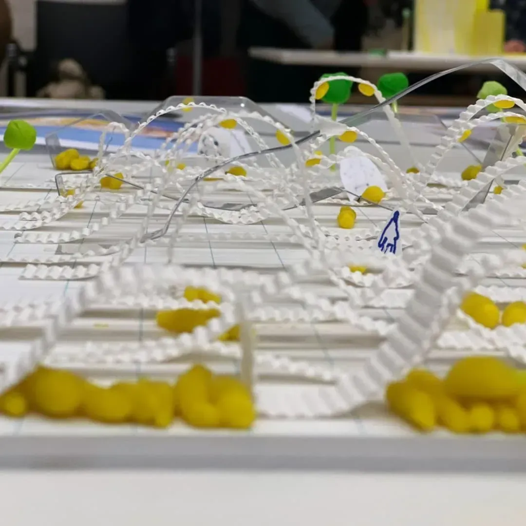 Modelo 3D de una ciudad con edificios blancos, estructuras amarillas y formas verdes parecidas a árboles.