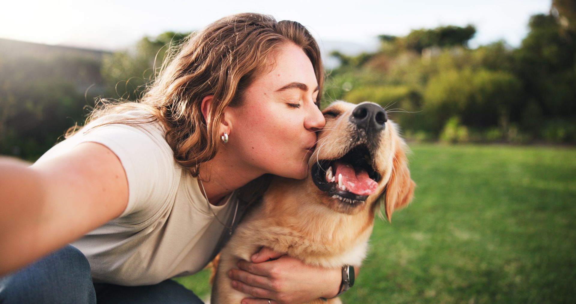 Une personne embrassant un golden retriever.