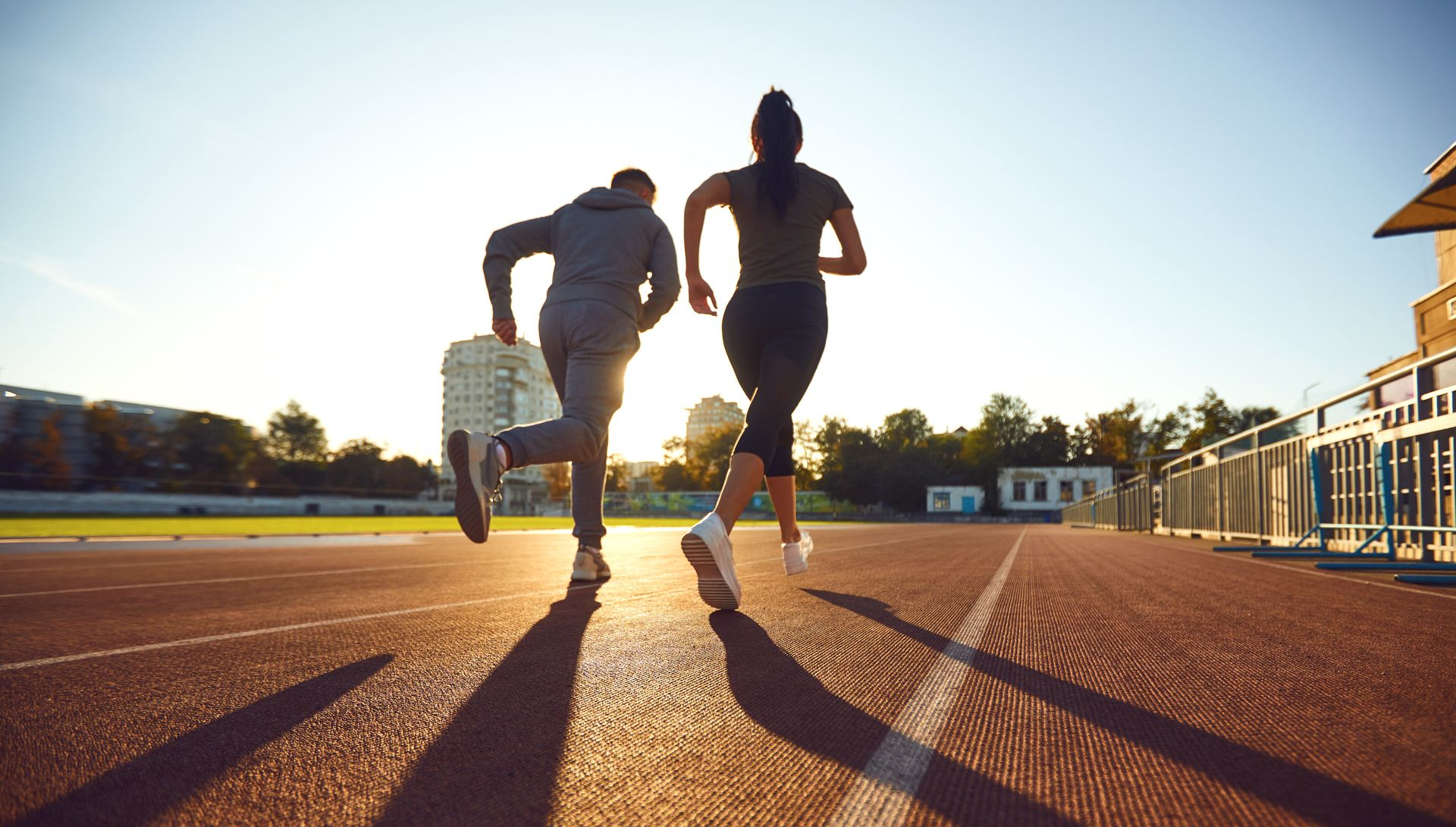 Deux personnes font du jogging sur une piste d'athlétisme.