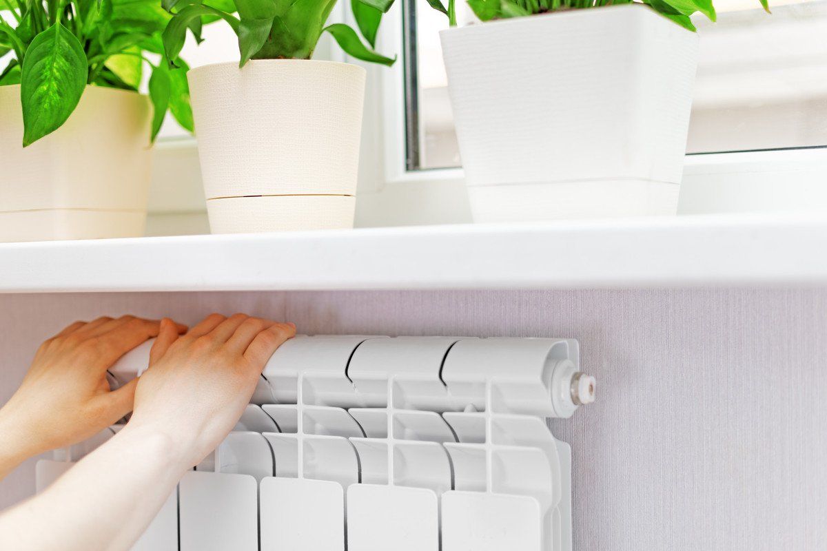 Deux mains sur un radiateur sous une fenêtre