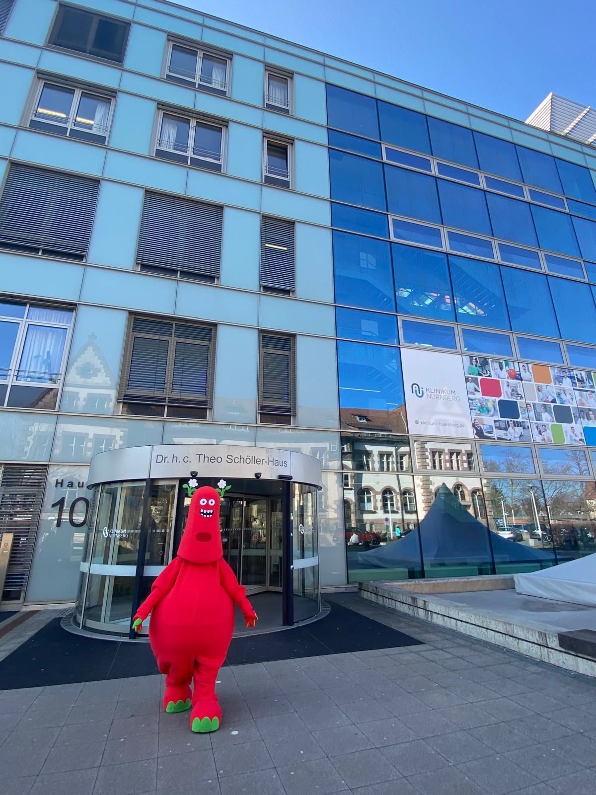 Ein rotes Maskottchen steht vor einem Gebäude mit der Nummer 10 darauf