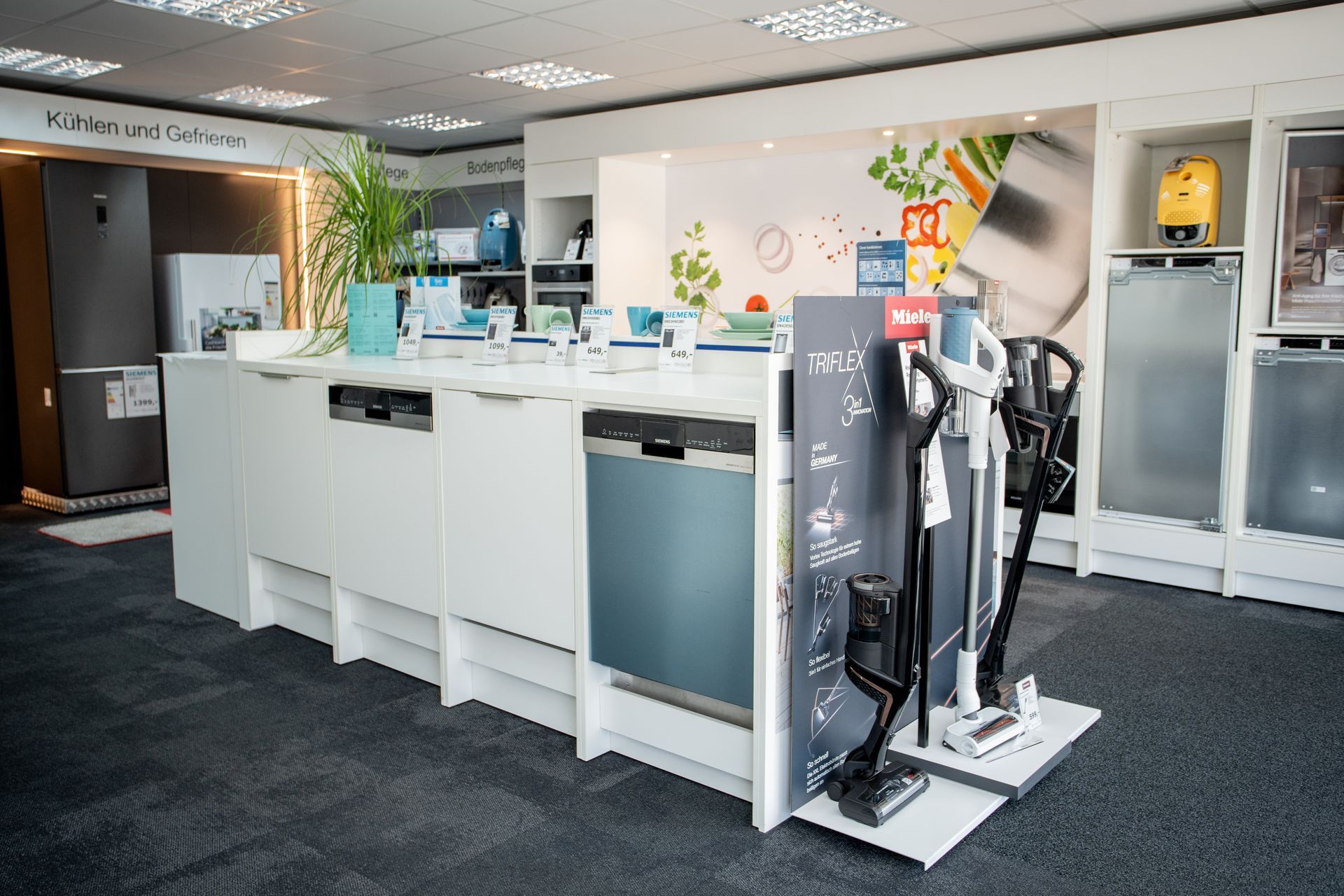 Weißer Küchenblock mit eingebauten Geräten und mehreren Staubsaugern.