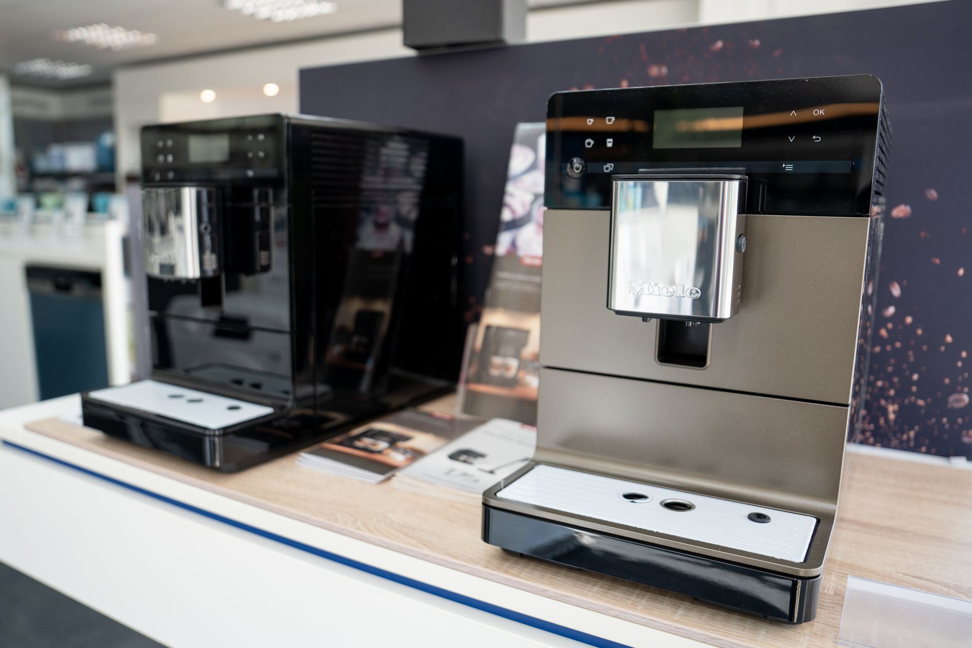 Zwei moderne Kaffeevollautomaten in Schwarz und Edelstahl stehen nebeneinander auf einer hellen Oberfläche.