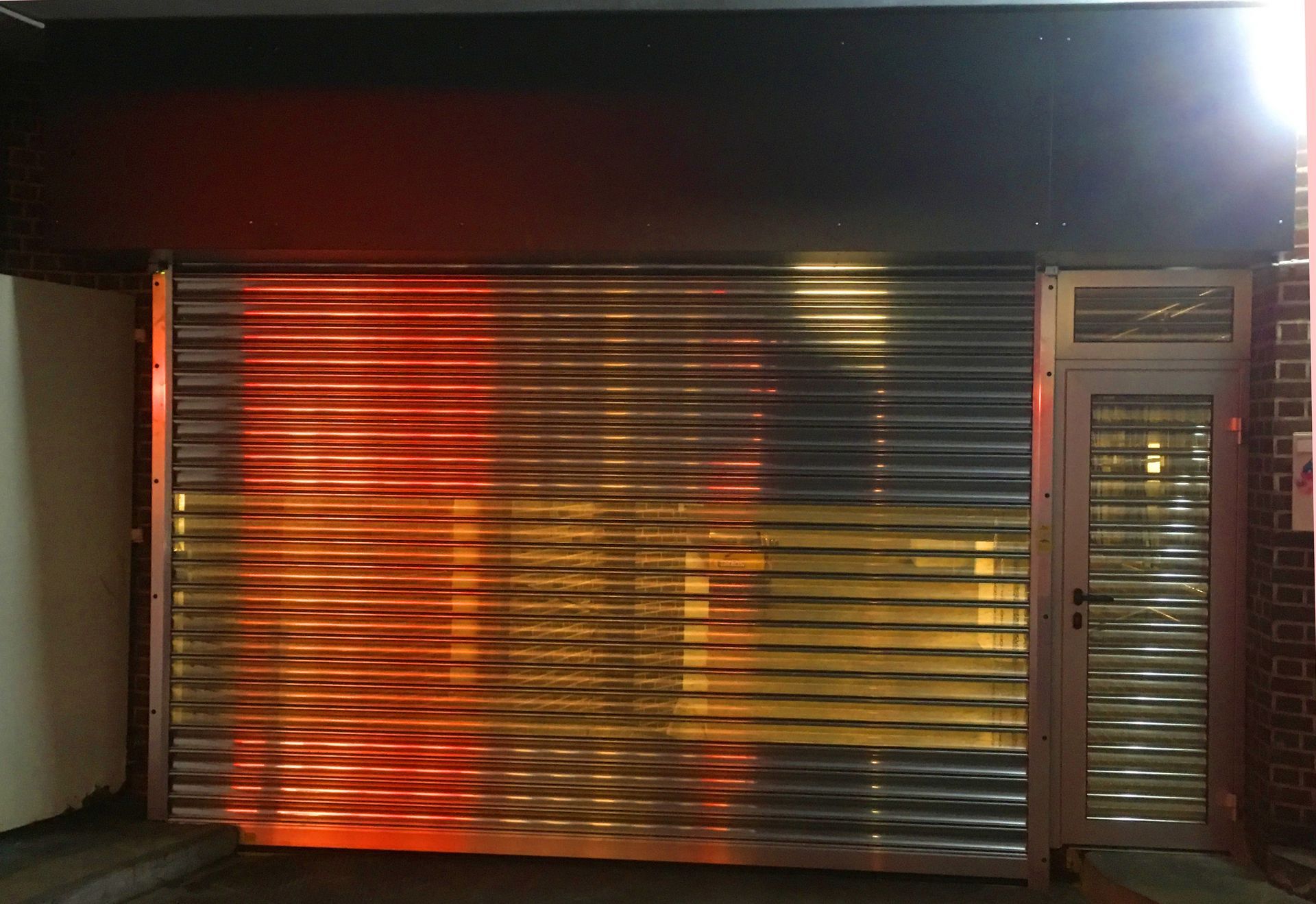 Backsteingebäude mit zwei großen, aufrollbaren Metalltoren, einer Rampe und einem kleinen Fenster.