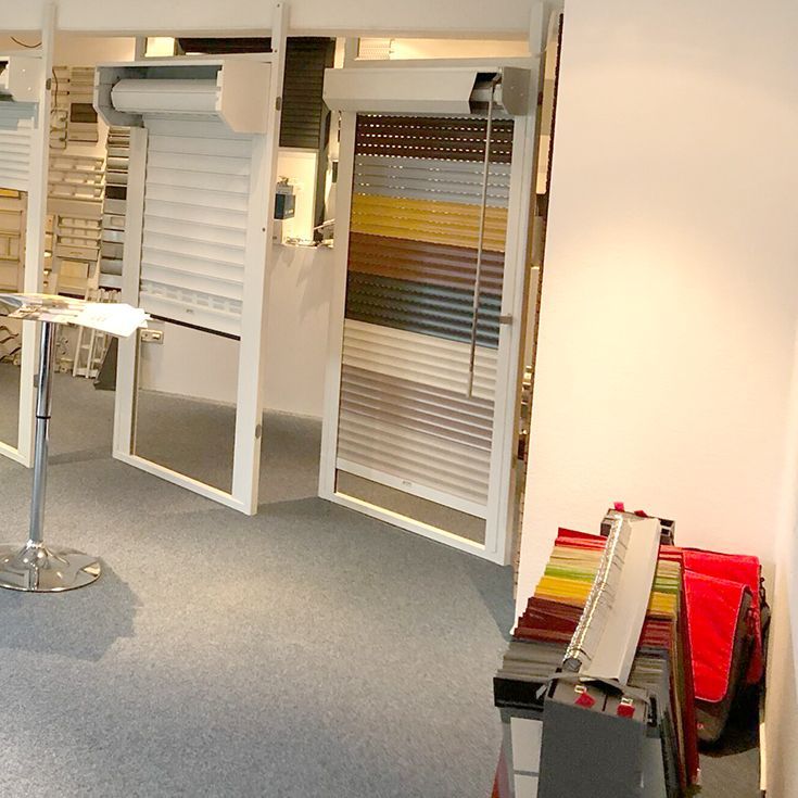 Ausstellung mehrerer farbenfroher Rollladenmuster in einem Ausstellungsraum.