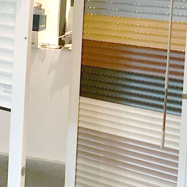 Ausstellung von farbenfrohen Lamellenjalousien in verschiedenen Farbtönen, darunter Weiß, Braun und Grau.