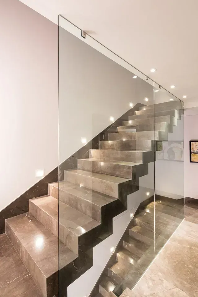 Una escalera moderna con barandilla de cristal en una casa.