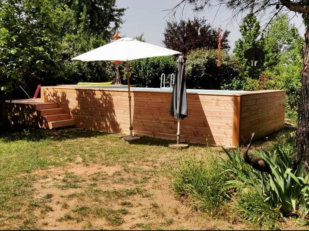Piscine avec habillage en bois et parasol