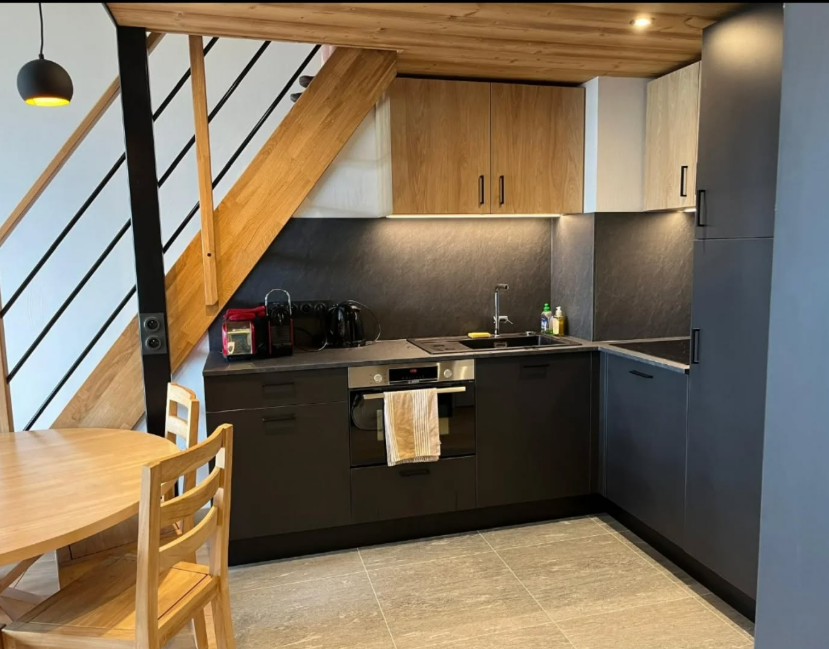 Cuisine noire sous un escalier en bois