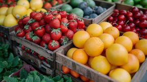 Cajas de madera llenas de frutas de colores: fresas, naranjas, limones, cerezas, ciruelas y verduras.