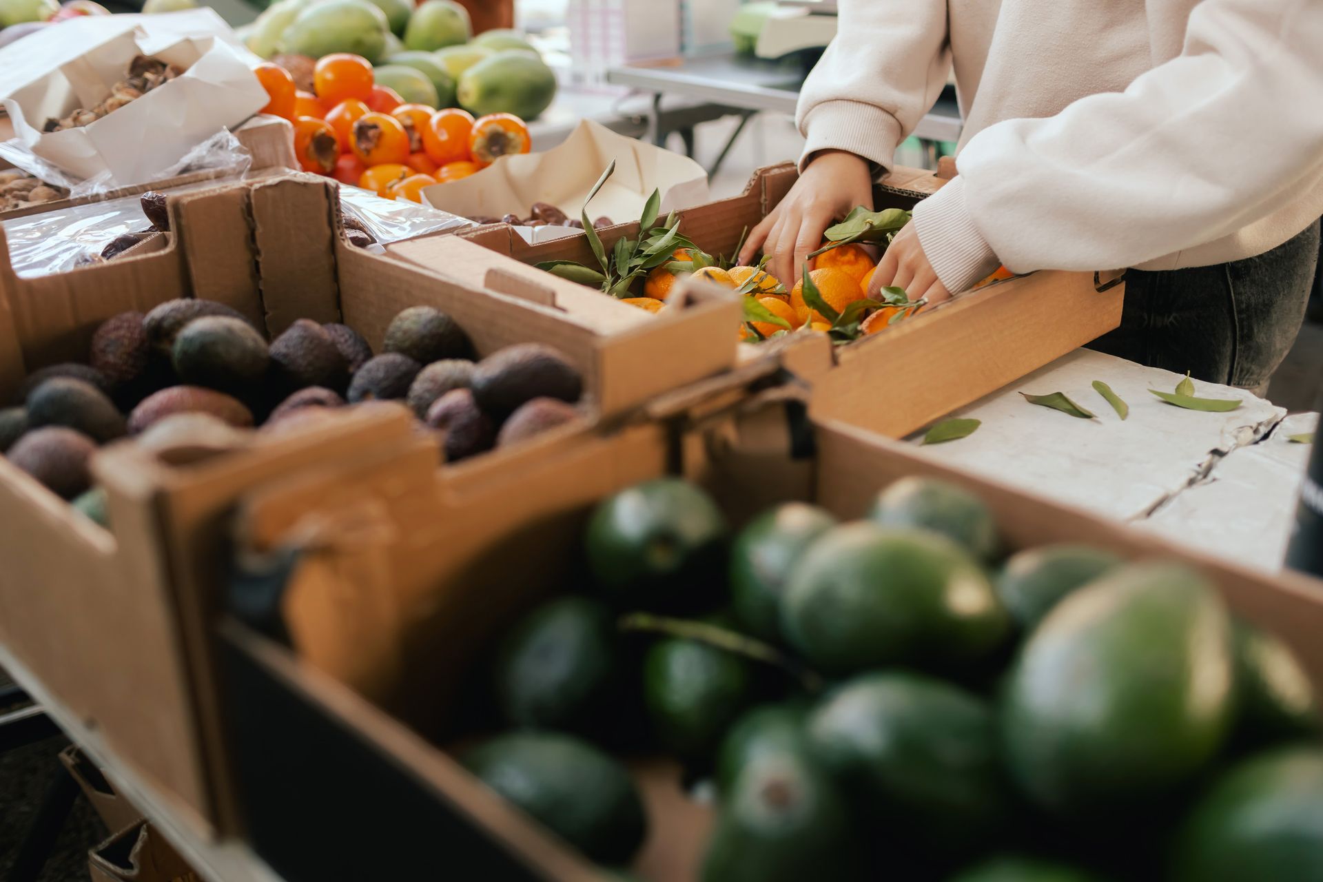 Puesto de productos con persona organizando frutas cítricas.