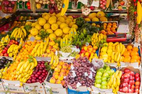 Exhibición de frutas: plátanos, limones, naranjas, uvas y otros productos en varios colores.