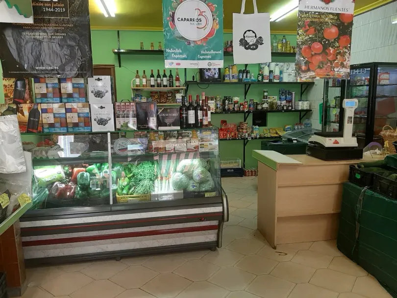 Interior de una pequeña tienda de comestibles con exhibición de productos, estantes de productos y un área de caja.