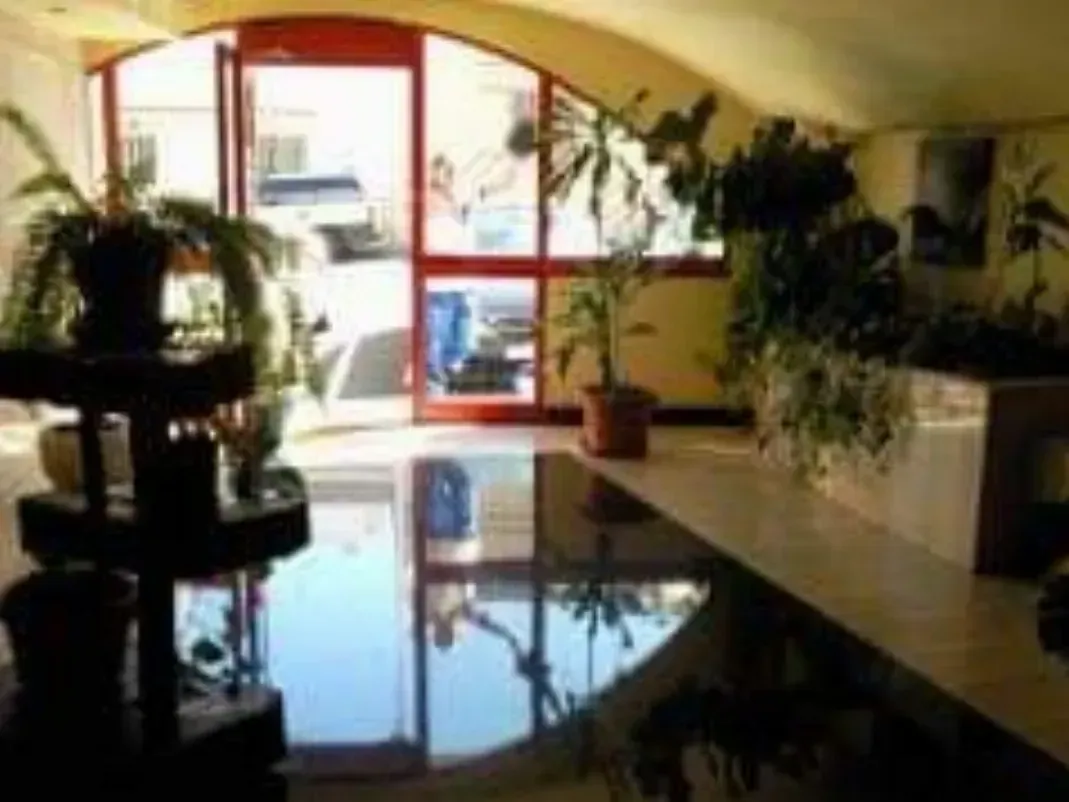 Una habitación con muchas plantas en macetas y una puerta roja.