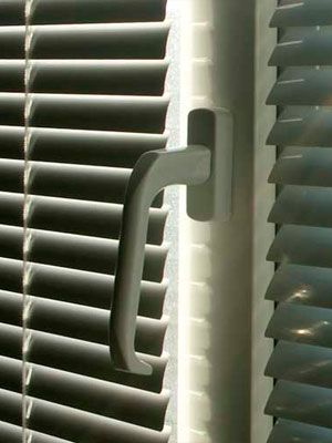 Un primer plano de una ventana con persianas y un tirador.