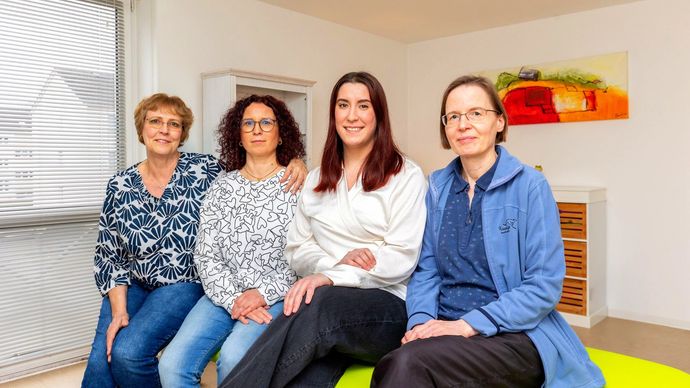 Eine Gruppe von Frauen sitzt nebeneinander auf einem Sofa.