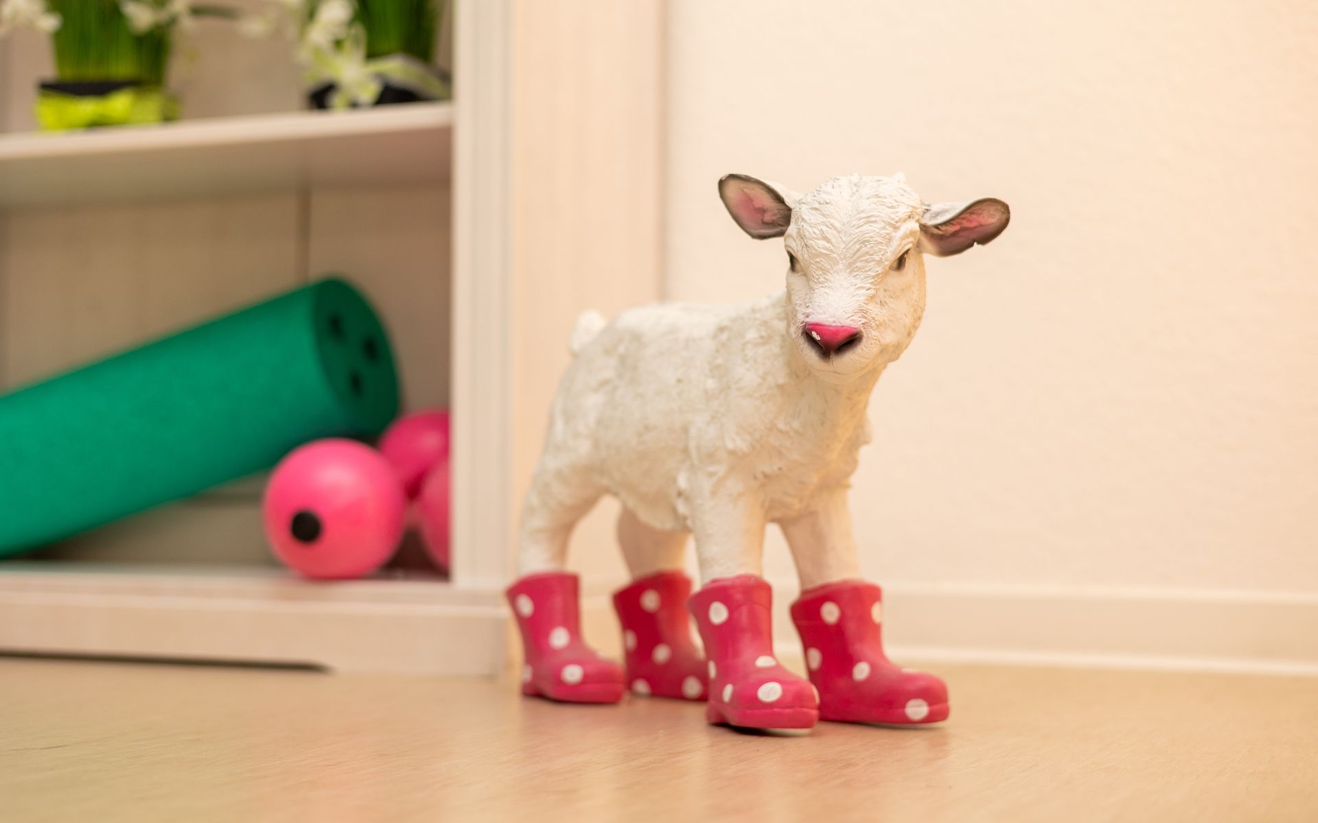 Eine Statue eines Schafs mit rosa gepunkteten Stiefeln.