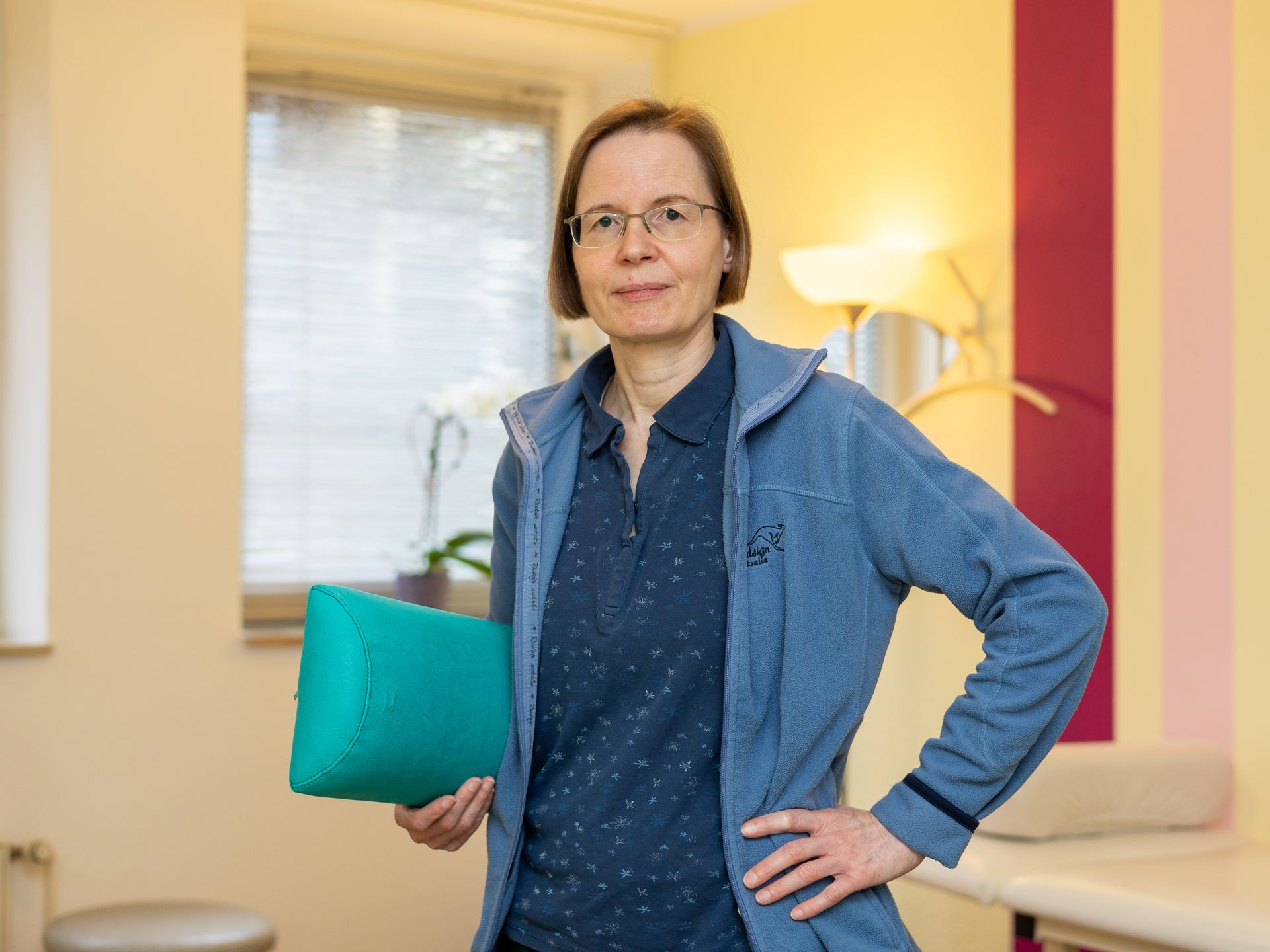 Eine Frau in einer blauen Jacke hält ein grünes Kissen.