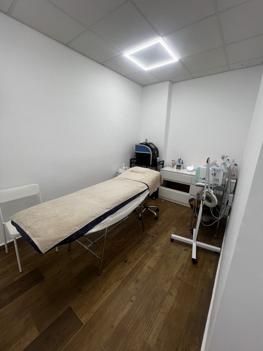 Sala de tratamientos con mesa de masajes, equipamiento médico y paredes blancas.