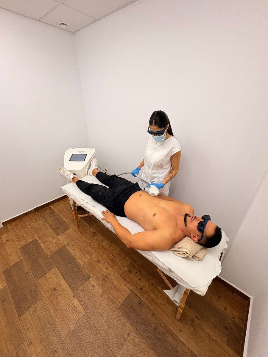 Hombre recibe tratamiento de depilación láser en las piernas en la clínica.