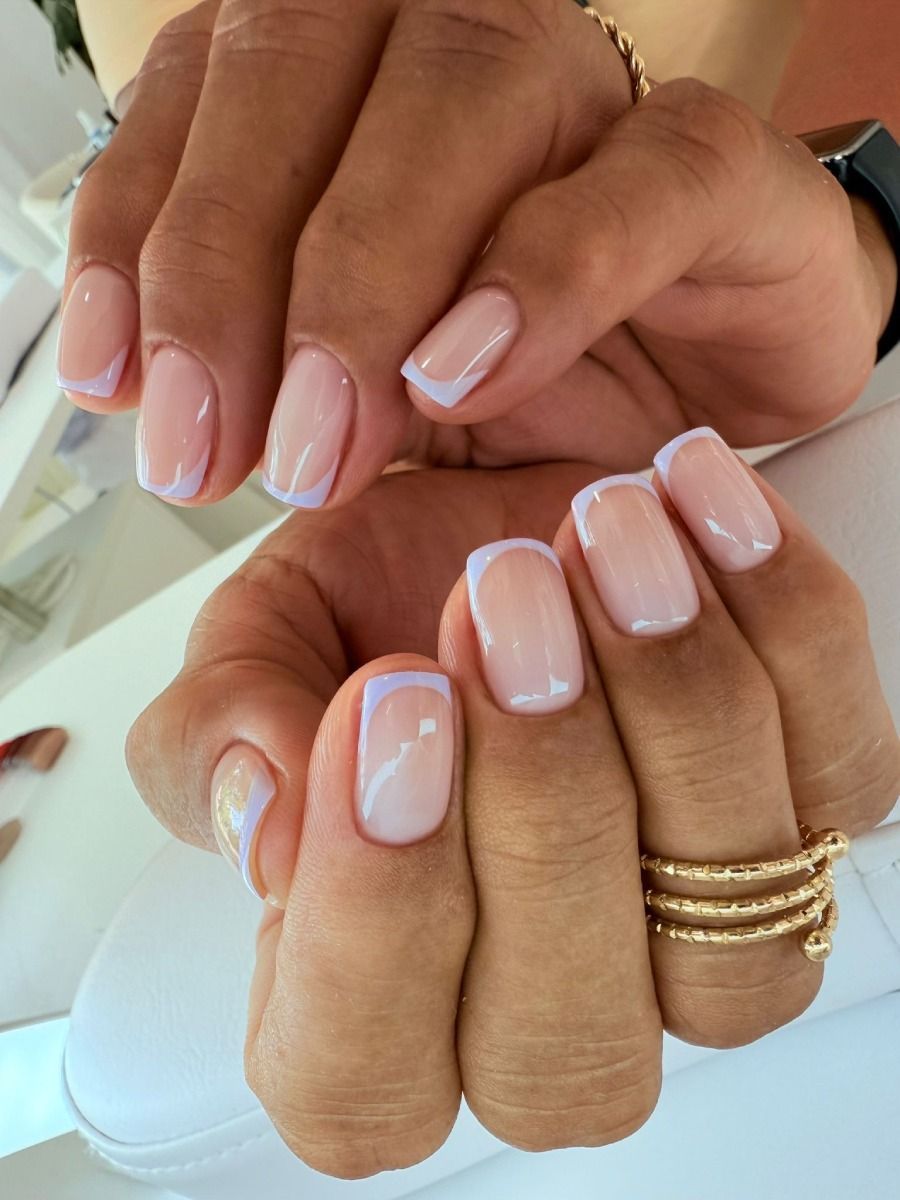 Manos con uñas de forma cuadrada en estilo manicura francesa, con base rosa pálido y punta fina blanca.