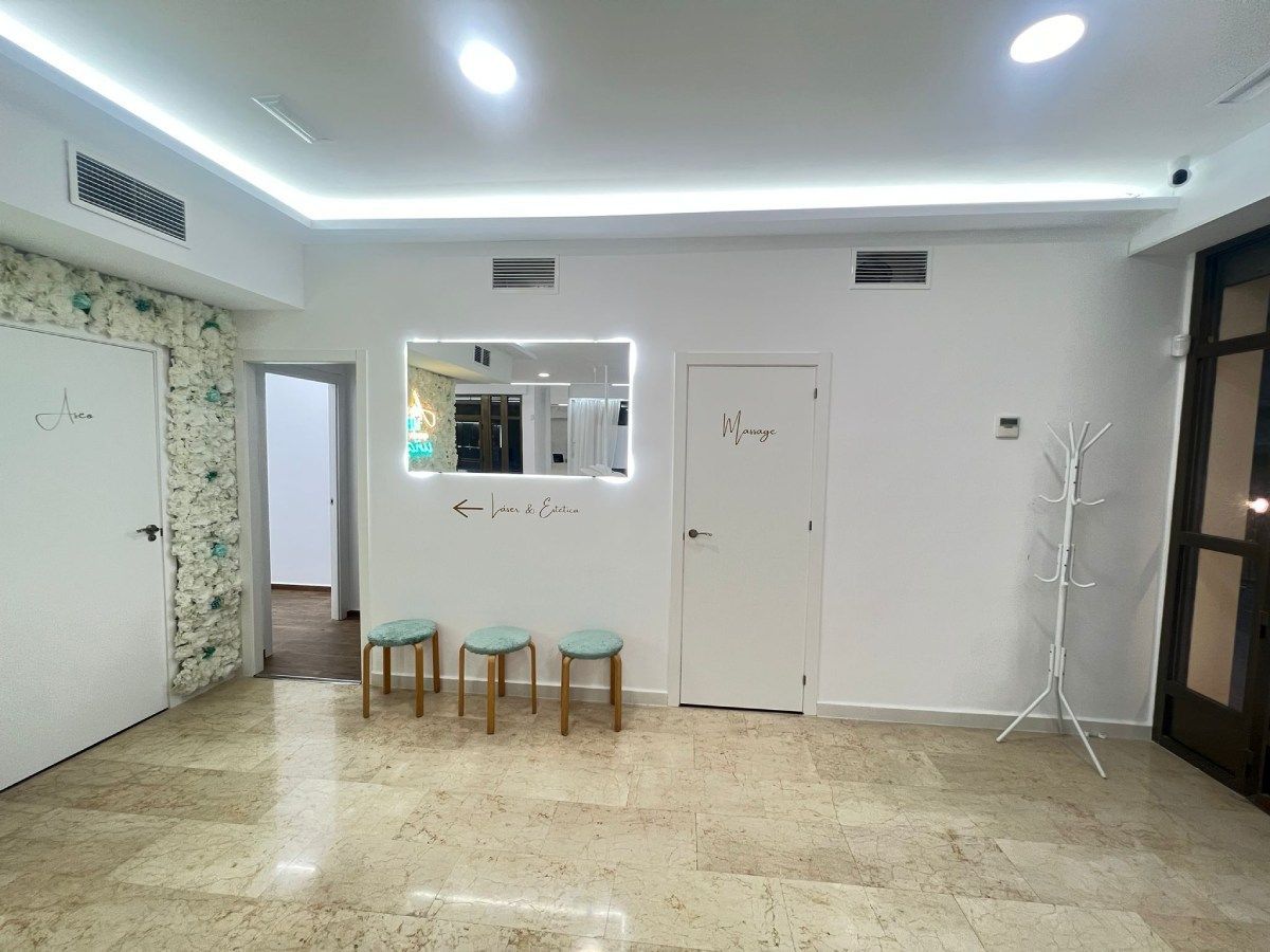 Área de recepción: paredes blancas, pisos de mármol, tres taburetes, espejo, puertas y perchero.