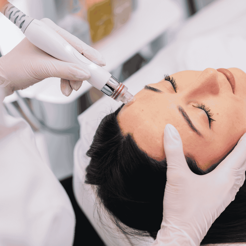 Persona que recibe un tratamiento facial con un dispositivo portátil en la frente, manos con guantes blancos.